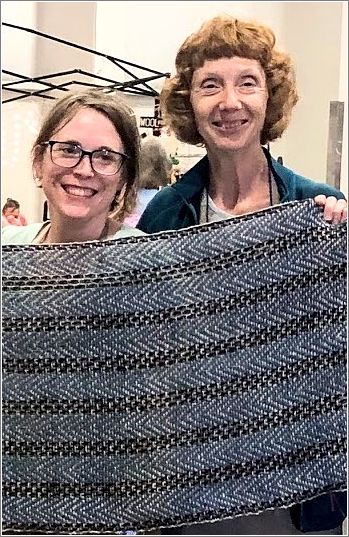 Marci Pippin and Rosalie Linse show off Team # 1s completed shawl. Photo: Aurora Colony Handspinners Guild.